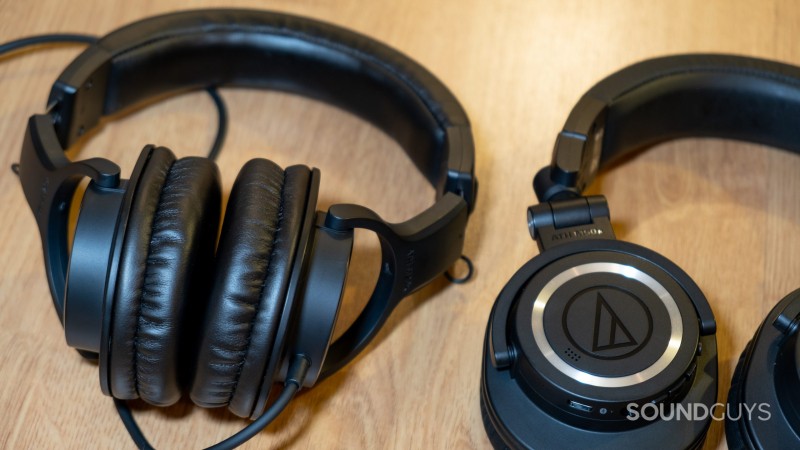The Audio-Technica ATH-M20x sitting next to the Audio-Technica ATH-M50xBT2 on a wood surface.