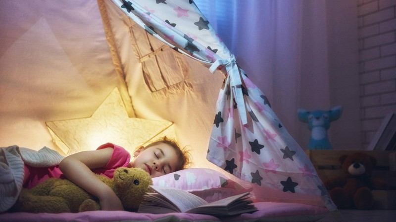 Mädchen schläft mit Nachtlicht im Zelt