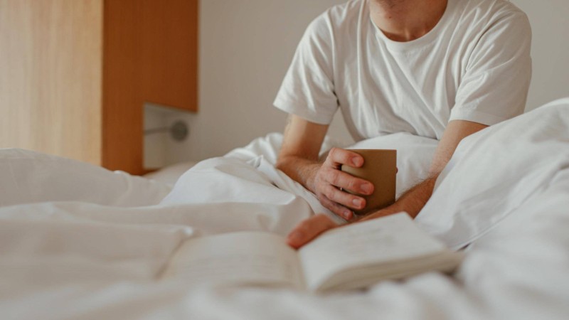 Menschen auf Bett mit Buch und Tee